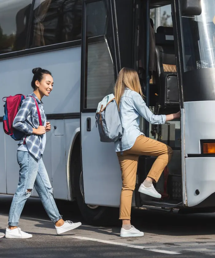 Passengers with backpacks boarding a charter coach